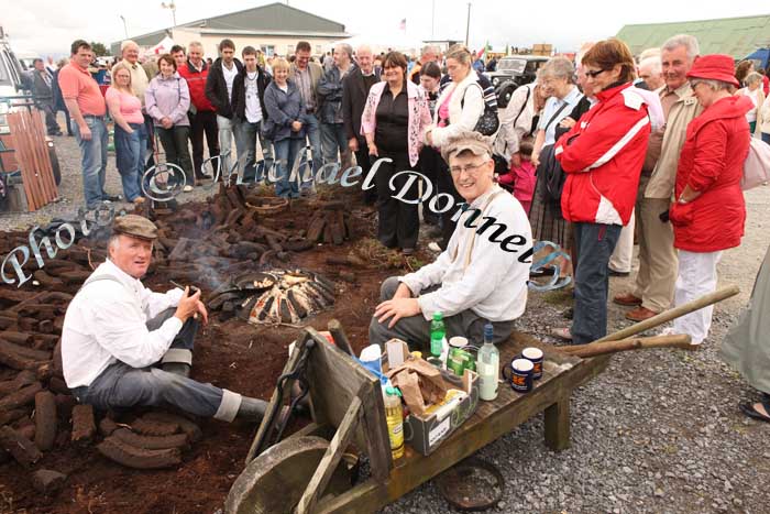 A crowd wait while eggs are boiled in a paperbay and sausages cook on the open turf fire at Claremorris Agricultural Show. Photo: Michael Donnelly.