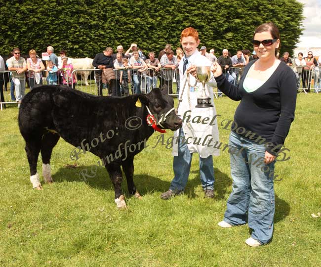 Ciaran Golden, Westport, (showing a Limousin/Belgian Blue cross heifer calf, ) (out of "Rocky" Limousin) winner of the Roundfort Young Stockperson Championship at Roundfort Agricultural Show is presented with the Kathleen Nally Memorial Perpetual Cup by Claire Nally. Photo:  Michael Donnelly