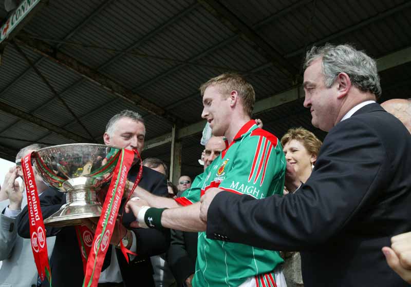 Lauri Quinn, President connacht Council presents  the Nestor Cup to Mayo captain David Heaney  in the Bank of Ireland Connacht Senior Football Championship in McHale Park Castlebar, watched by (partly hidden), Dr Martin McAleese and Uachtaran na hireann, Mary McAleese and Dr Mickey Loftus former President of the GAA