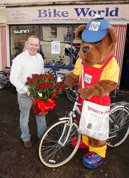  On Yer Bike! Newsybear tries out a bicycle as Peadar Leonard holds his bucket of roses. Photo Michael Donnelly.